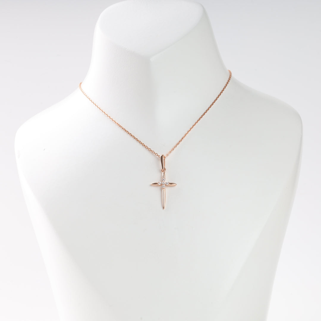 Rose gold cross pendant necklace with a single clear stone, displayed on a white bust. Cross necklace, rose gold jewelry.