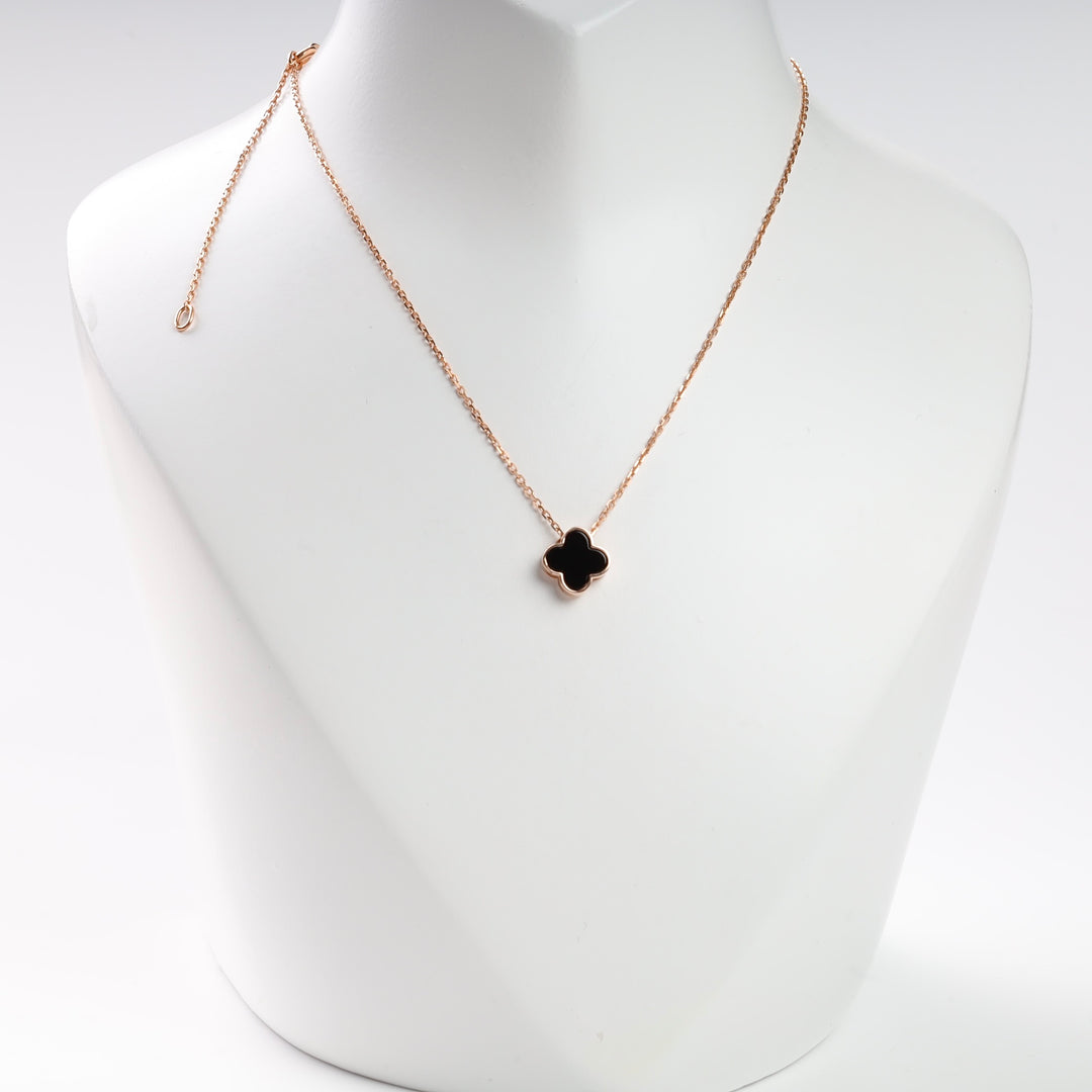 Rose gold necklace with black clover pendant displayed on a white bust.