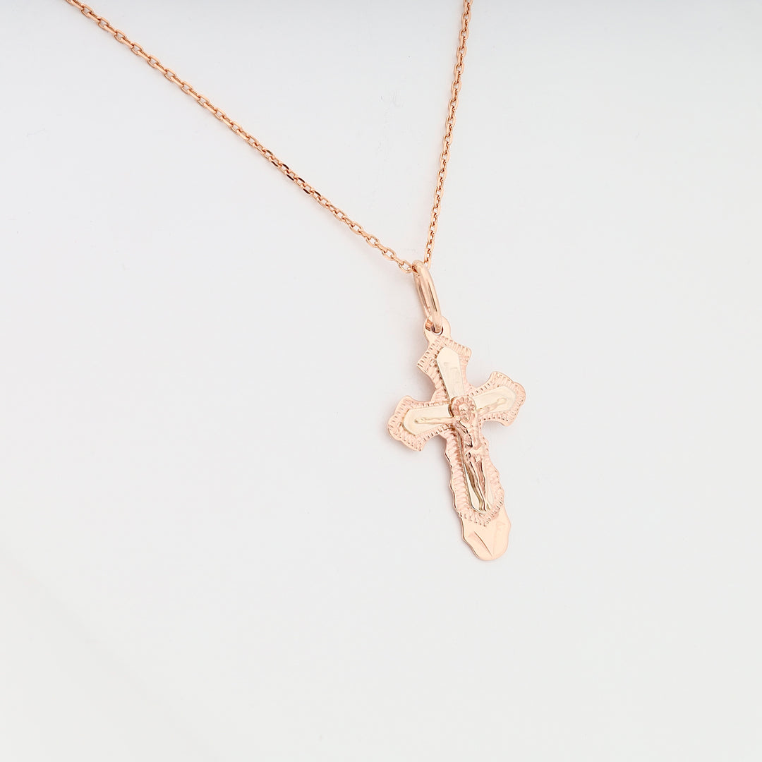 Rose gold crucifix pendant necklace with Jesus figure on a delicate chain, shown on a white background.