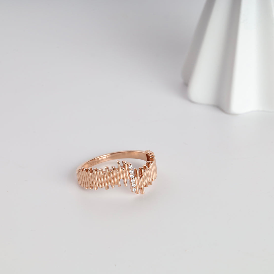 Rose gold ring with vertical bar design and small clear crystals, modern geometric band jewelry on white background.