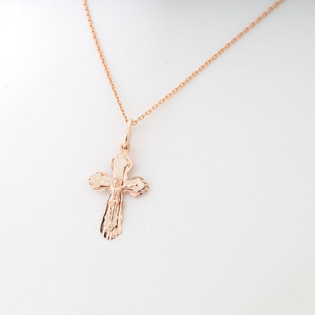 Rose gold chain necklace with a polished crucifix pendant displayed on a white background.