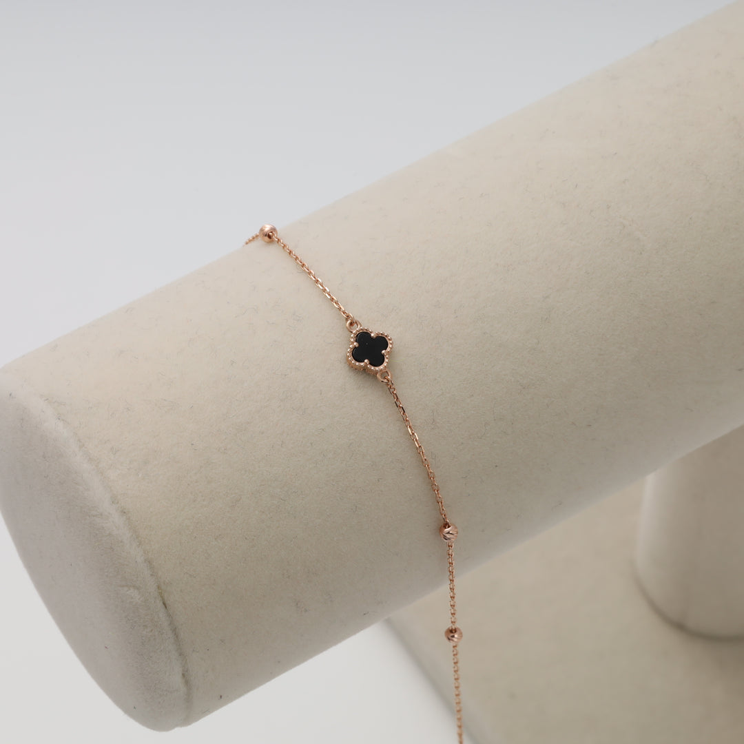 Delicate 14k gold bracelet with black clover charm on display stand, minimalist Ukrainian Jewelry, dainty gold chain bracelet.