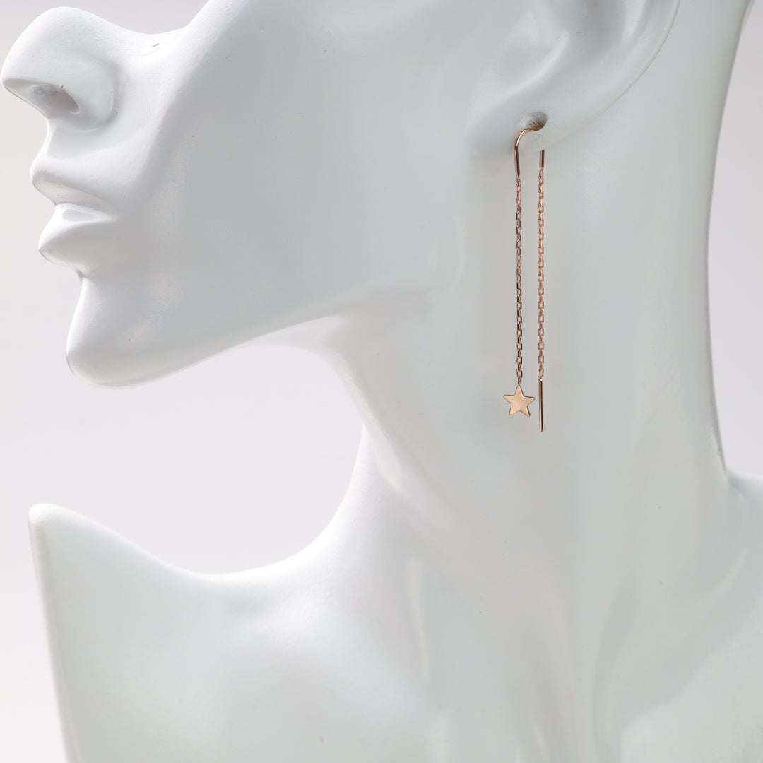 Gold chain earrings with a star charm on a white mannequin.