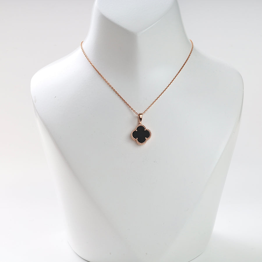 Gold chain necklace with a black quatrefoil pendant displayed on a white bust, clover charm jewelry.