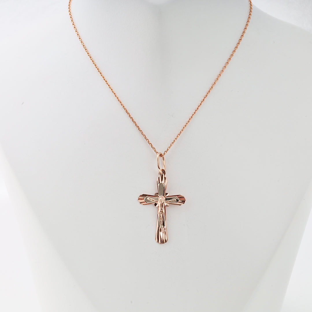 Rose gold crucifix pendant necklace with Jesus motif displayed on a white bust, Catholic cross jewelry.