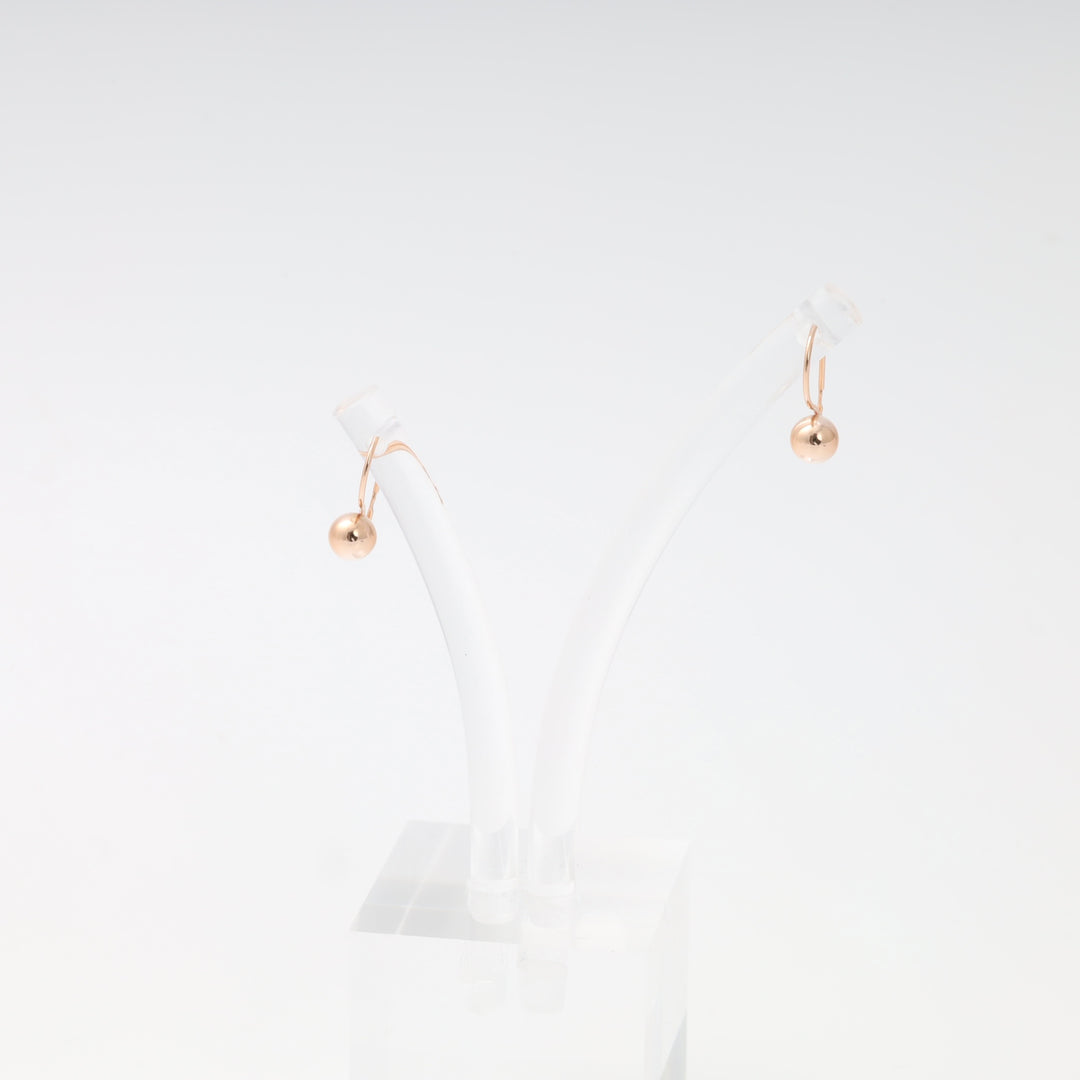 Minimalist 14k gold ball drop earrings on hooks displayed on a clear stand, Ukrainian Jewelry, delicate gold dangle earrings.