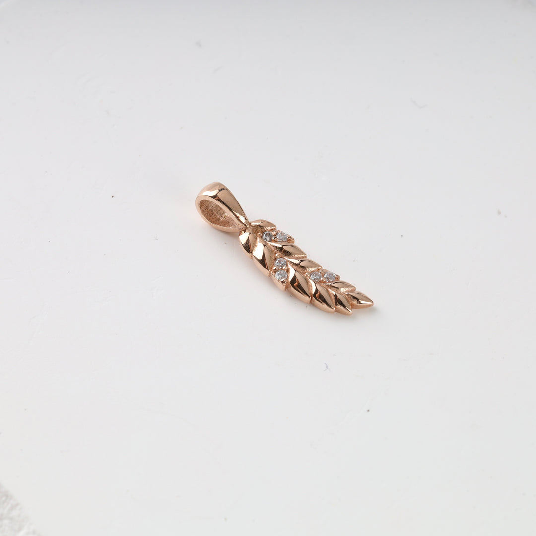 Gold leaf pendant with small clear crystals arranged in a row, displayed on a plain white background.