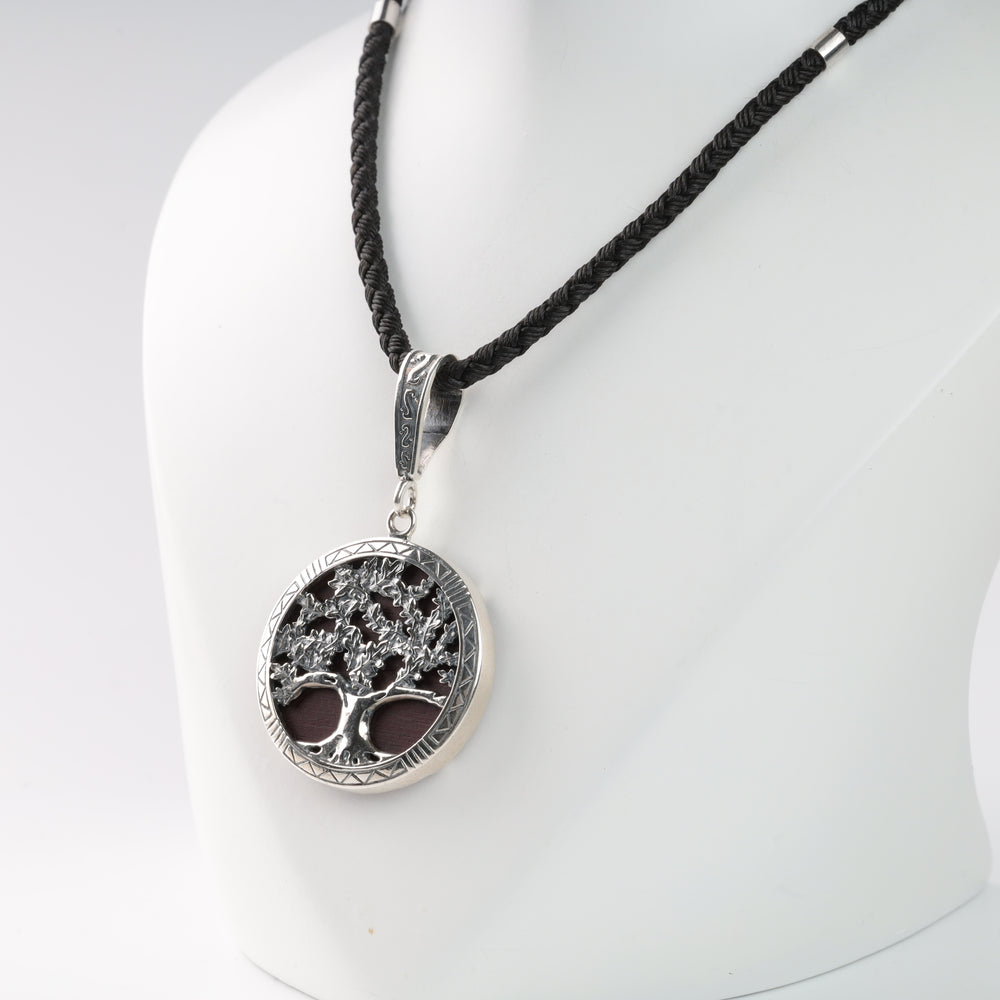 Silver tree of life pendant on a black braided cord necklace.