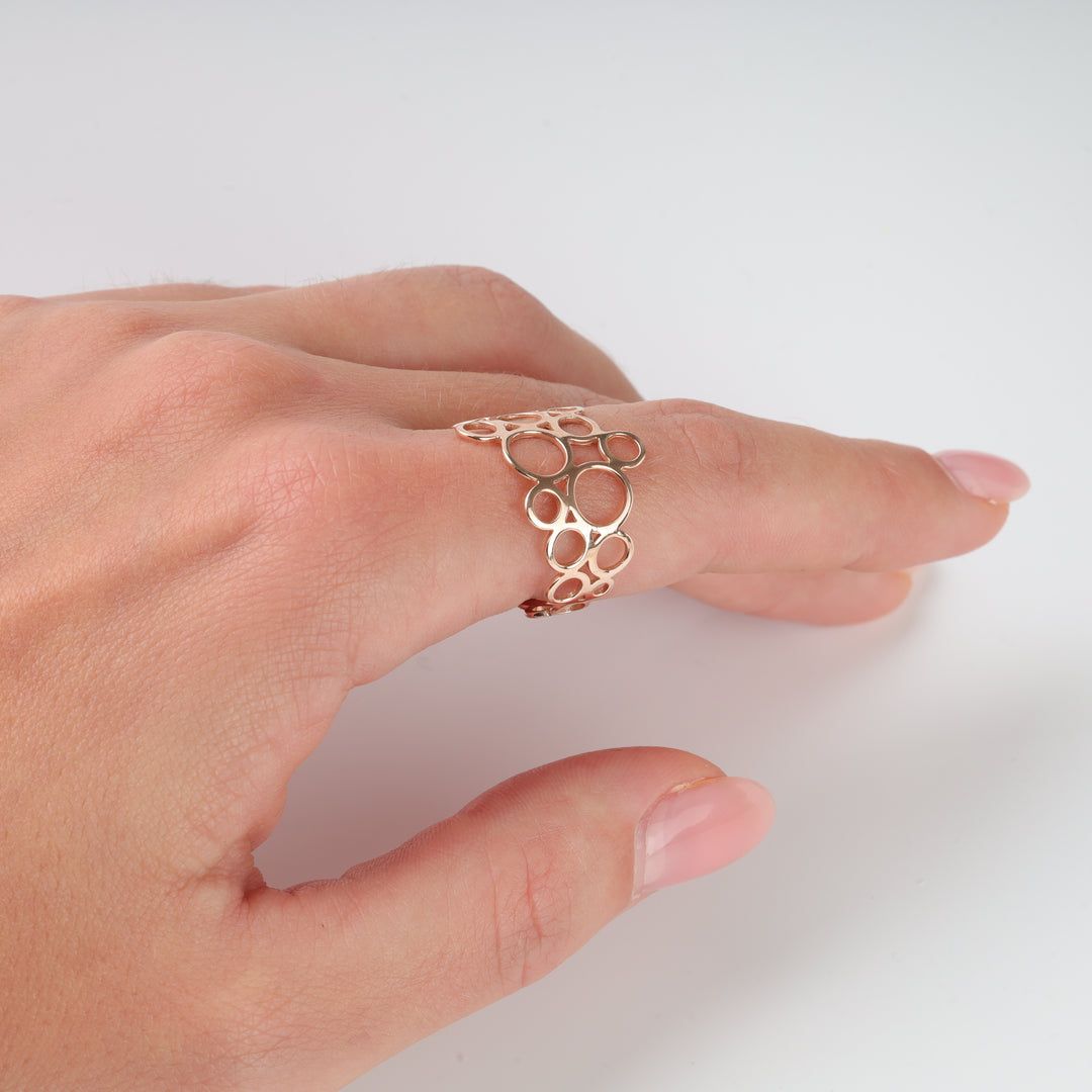 Openwork rose gold ring with organic bubble motif on a hand, minimalist gold jewelry, modern statement ring.