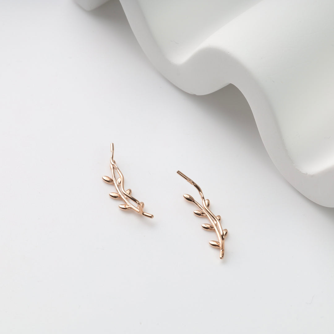 Pair of rose gold vine ear climbers with leaf motif on white background, rose gold ear climbers, leaf earrings.
