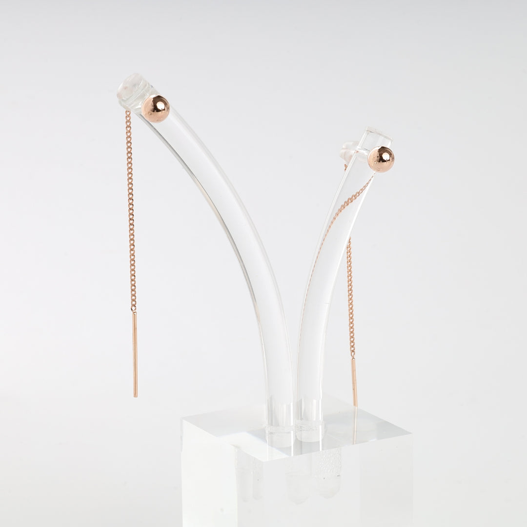 Pair of rose gold threader earrings with fine chain and bar ends, displayed on a clear acrylic stand.