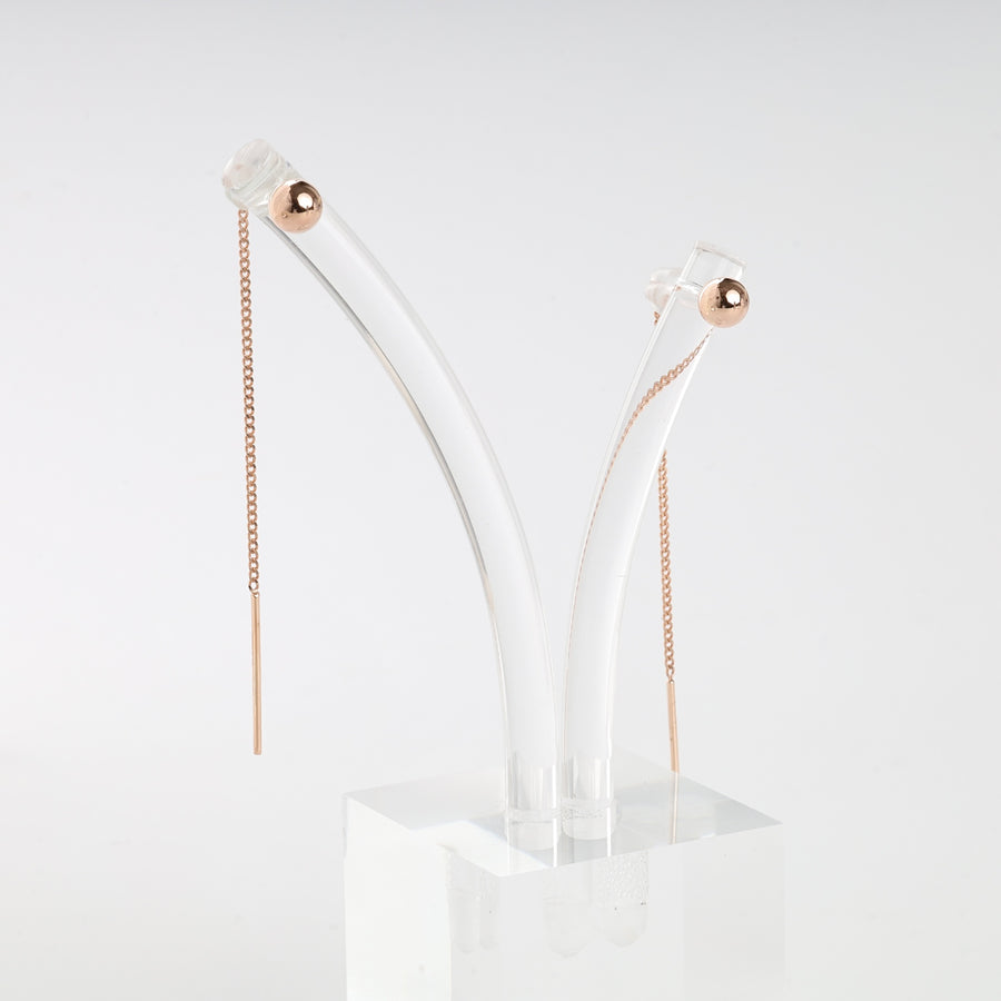 Pair of rose gold threader earrings with fine chain and bar ends, displayed on a clear acrylic stand.