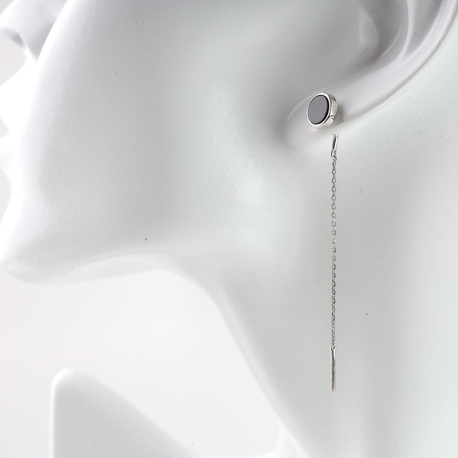 Single silver chain drop earring with round black stud, shown on a white mannequin head, minimalist jewelry.