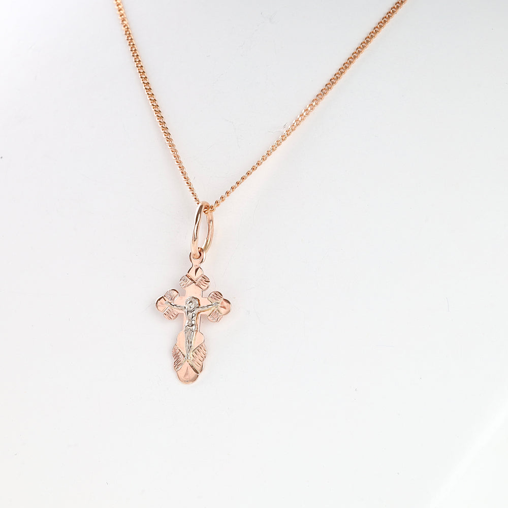 Rose gold crucifix pendant necklace with detailed Jesus motif on a simple chain, shown against a white background.