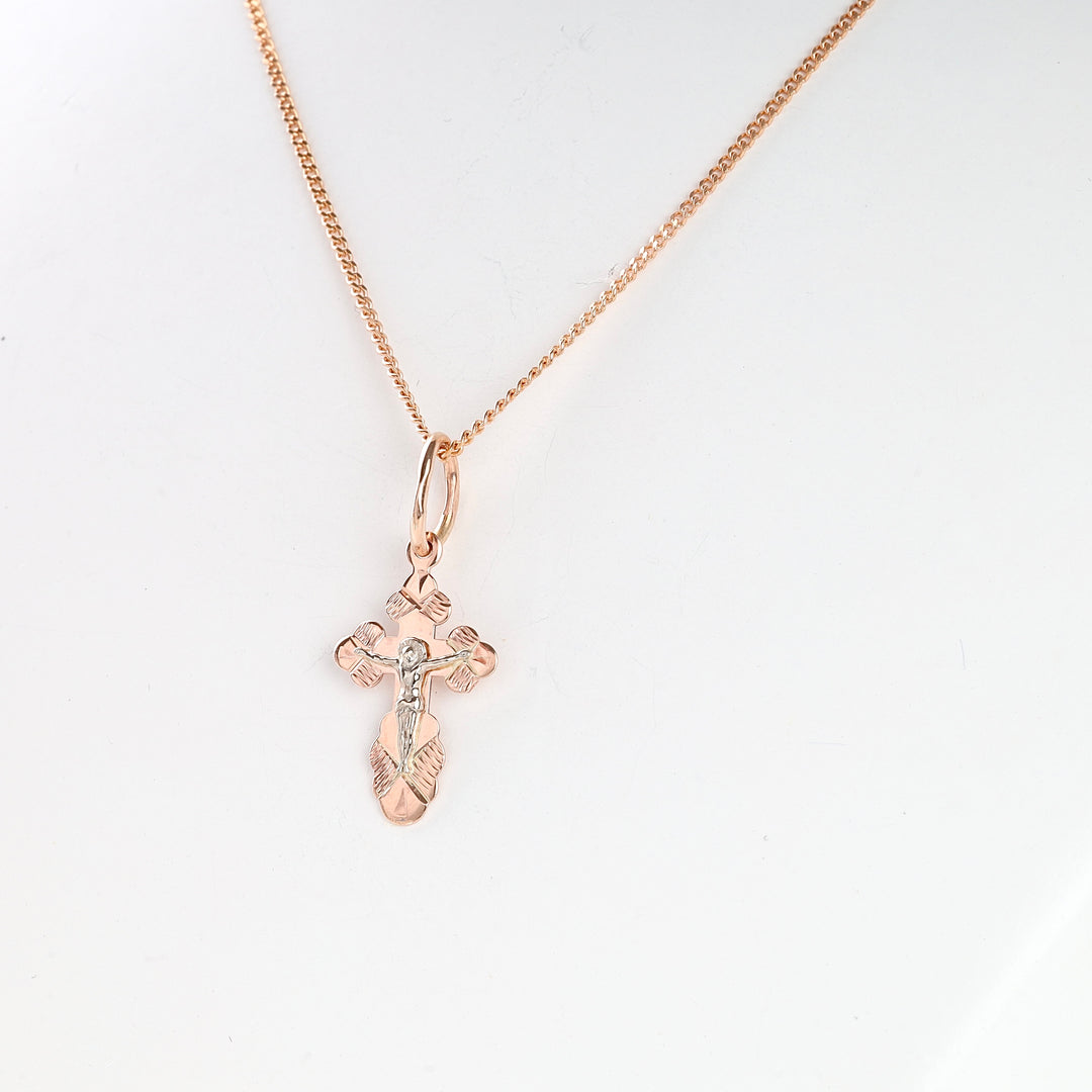Rose gold crucifix pendant necklace with detailed Jesus motif on a simple chain, shown against a white background.