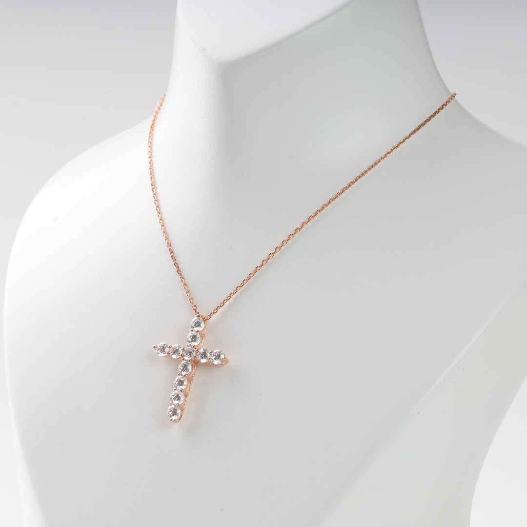 Rose gold chain necklace with a crystal-studded cross pendant displayed on a white mannequin.