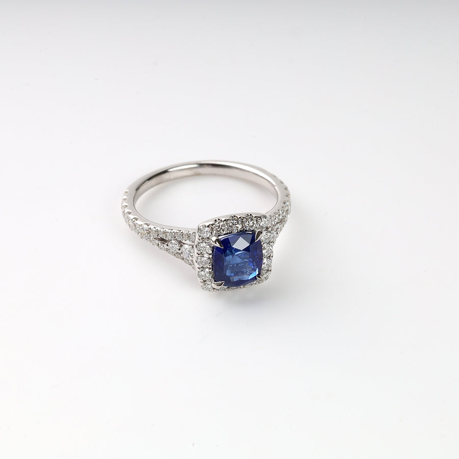 Silver engagement ring with a square blue sapphire center stone and clear diamond accents on a white background.
