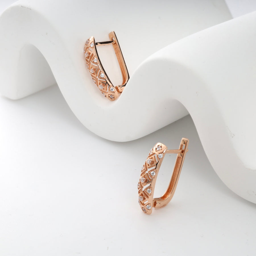 Rose gold diamond huggie earrings with lattice design on white background.
